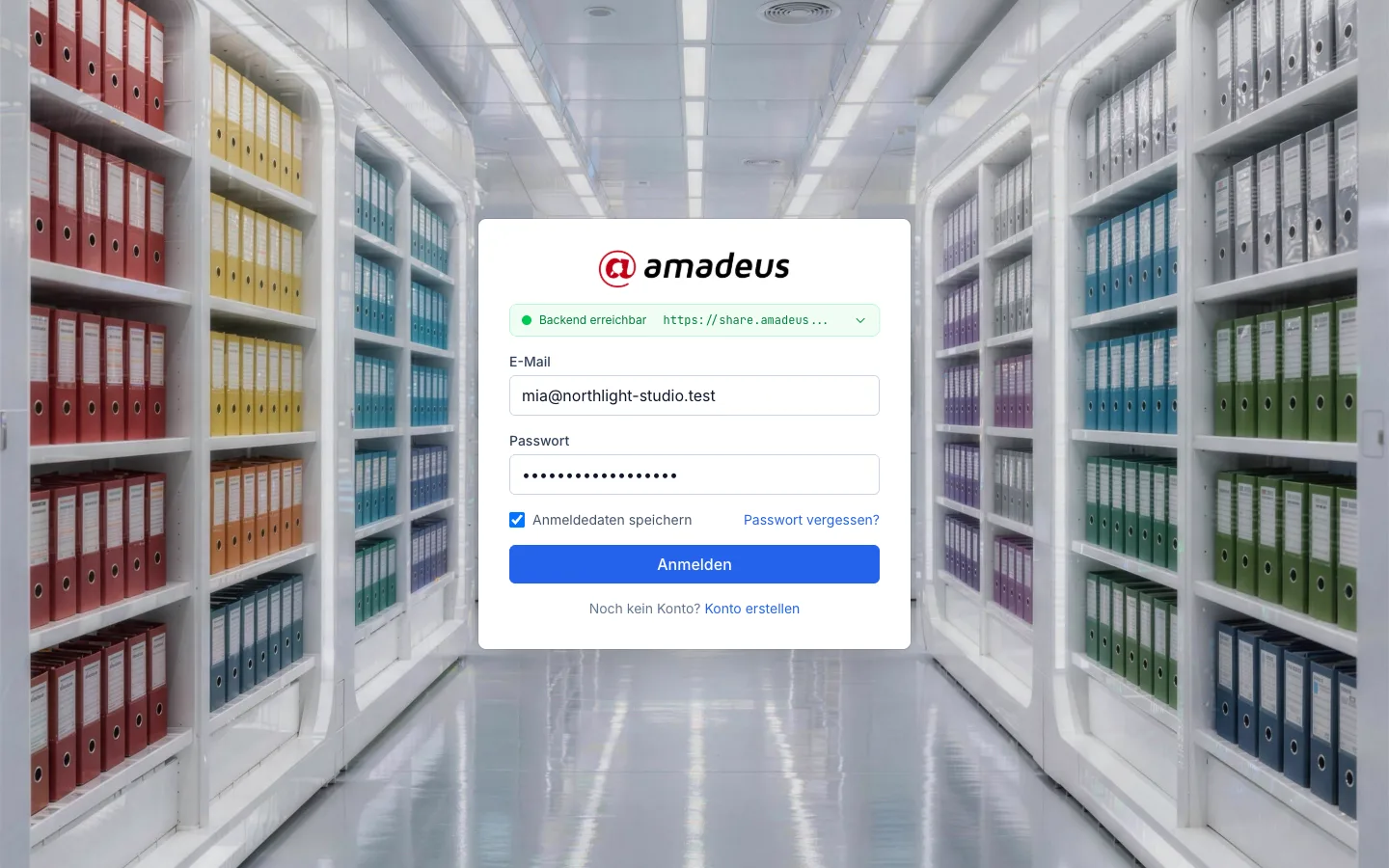 Die Anmeldung: E-Mail, Passwort, „Anmeldedaten speichern“ und die Schaltfläche Anmelden vor dem Bild eines hellen Archivs.